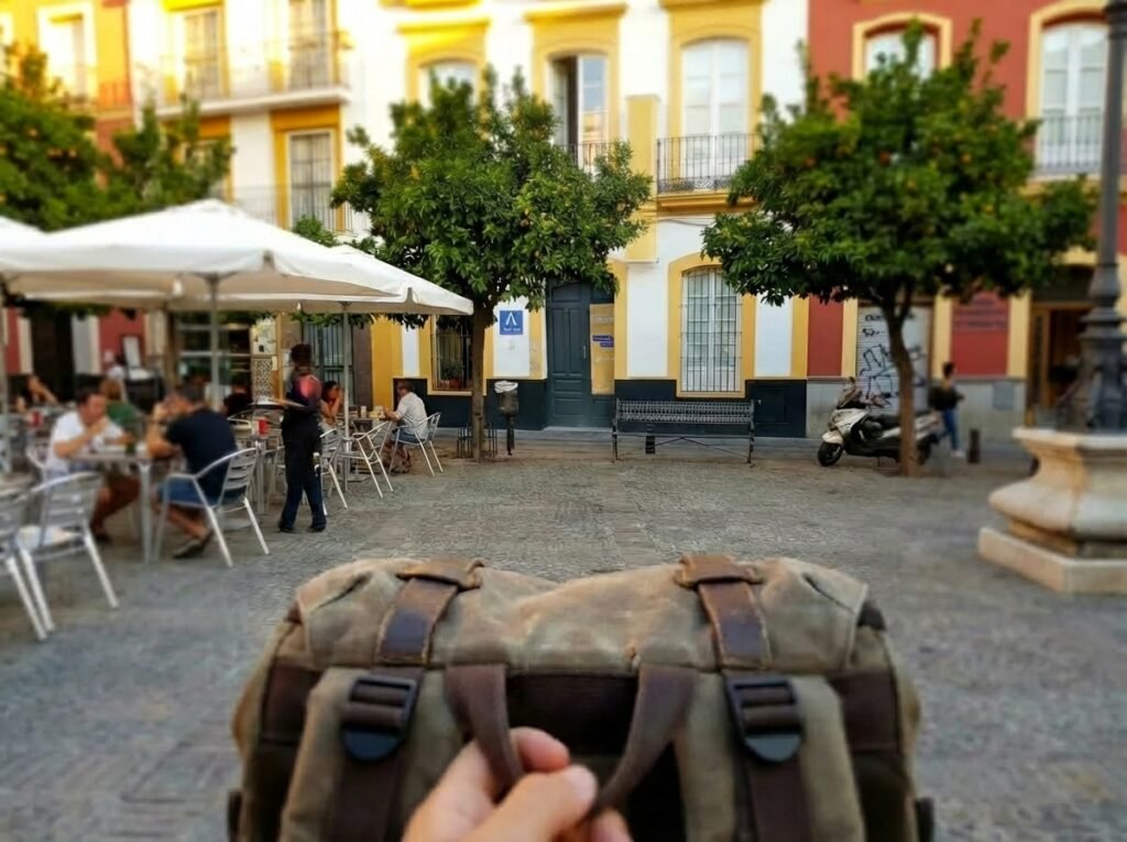 El exterior y cómo llegar al Onefam Centro Hostel de Sevilla, en el casco antiguo, con naranjos y viajeros en la puerta