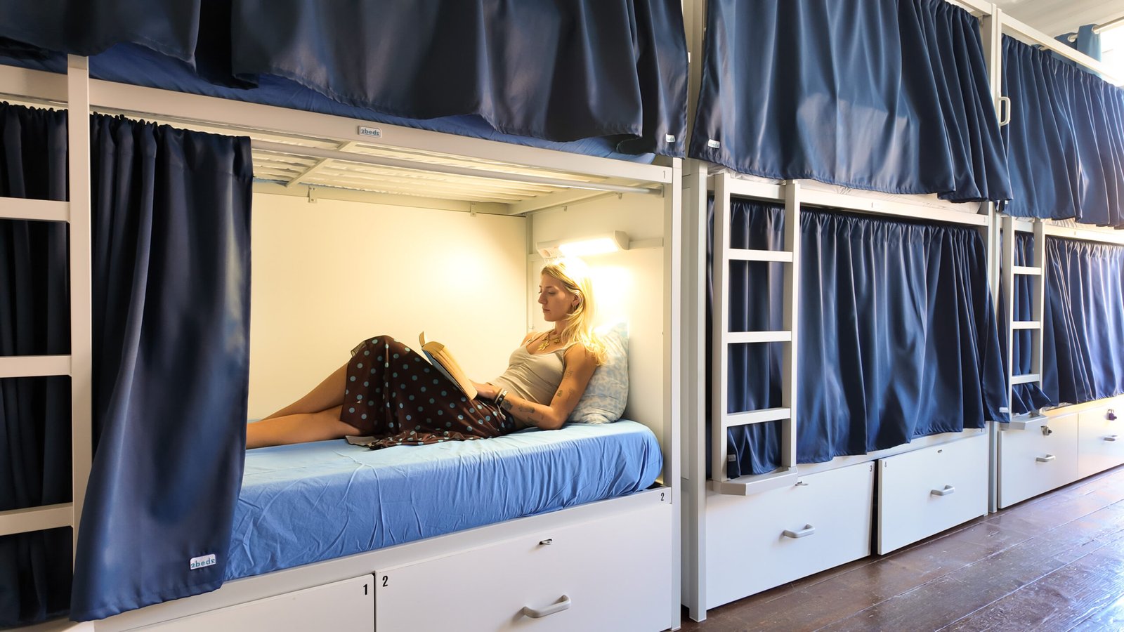 05-clerigos-female-guest-reading-dorm-bed-onefam-hostels-clerigos-porto
